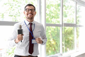 Male reporter with badge and microphone in studio
