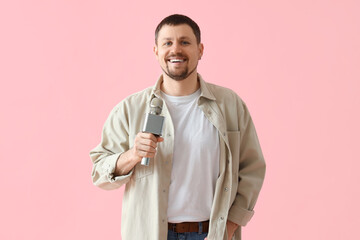 Male reporter with microphone on pink background