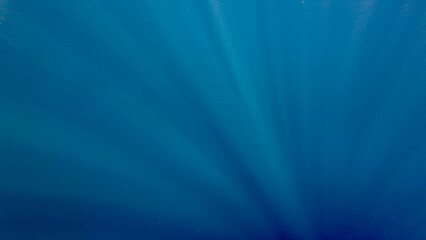 Blue abstract background. Sun rays in the water column. Water texture. Rays of the sun against the...