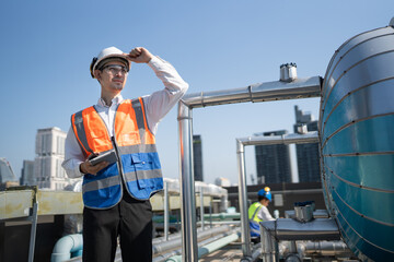 Portrait Asia male engineer in protective workwear is performing a conducts system check with use...