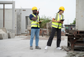 Portrait African engineer man use clipboard and Hispanic latin engineer woman use tablet computer checking precast cement at precast cement outdoor factory	