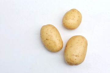 Three potatoes, on a white table, root vegetable, vegetarianism, food, vegetables, free space, place for text, top view, background