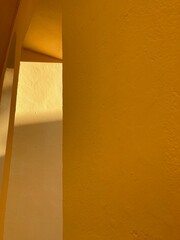 Abstract yellow geometric architectural forms. Modern buildings in the sun with deep shadows. Ochre shades of plaster with 3D effects of lighting and shapes. Minimalism in architecture. No filters.