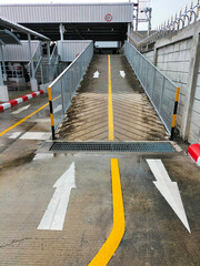 White arrows indicate directions outside an industrial building. Yellow painted motorbike parking lot between parallel yellow lines on abstract cement background