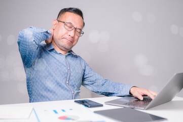 Business stress concept. The sleepy businessman sits in the office, an adult person working on his laptop, struggling to stay alert in the workplace.