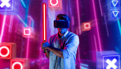 Energetic man with VR glasses fencing neon sword with music block. Skilled person playing a game...