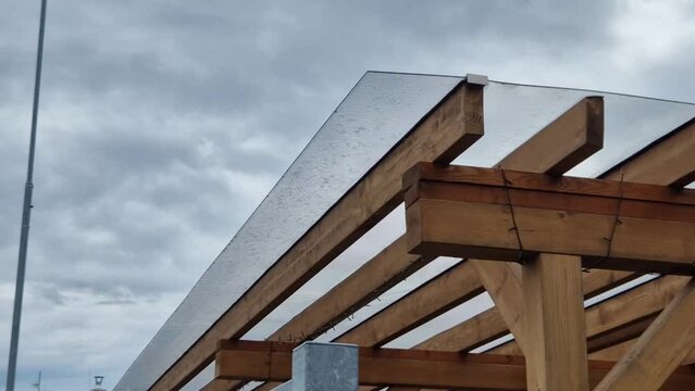wooden construction of the bus stop, shelter of a gazebo pergola. the roof and walls are lined with polycarbonate plexiglass glass is anchored with stainless steel connectors. ceiling glass is visor