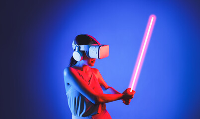 Smart female standing wearing VR headset connecting metaverse, future cyberspace community technology. Elegant woman firmly holding laser saber seriously while play sword-fighting game. Hallucination.