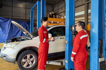 Two asian technician working with car lift machine for lift a car up to check wheel and change...
