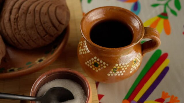 Adding a spoon of sugar to the coffee in a mexican clay jar