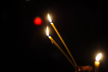Details with burning candles in the hands of a person during a religious ceremony