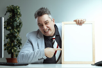 Spiky-haired man aggressively points at blank whiteboard