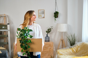 Caucasian woman holding a moving cardboard box to settle in her new home. Student residence relocation.
