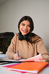 Portrait of a smiling female college student with braces studying at home.