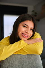 Latin female teenager with braces smiling and looking at camera.
