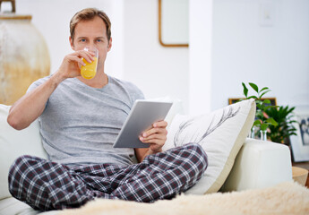 Portrait, orange juice and man with tablet, pajamas and relax with morning news, digital app and...