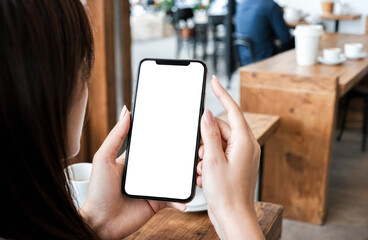 Cellphone mockup. Person in cafe hold cell phone, screen blank and white, copy space for text or app display, wooden tables, coffee cups, relaxed atmosphere surround