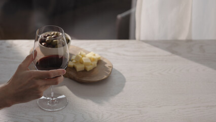 Man hand take red wine in wineglass with antipasti on white oak table