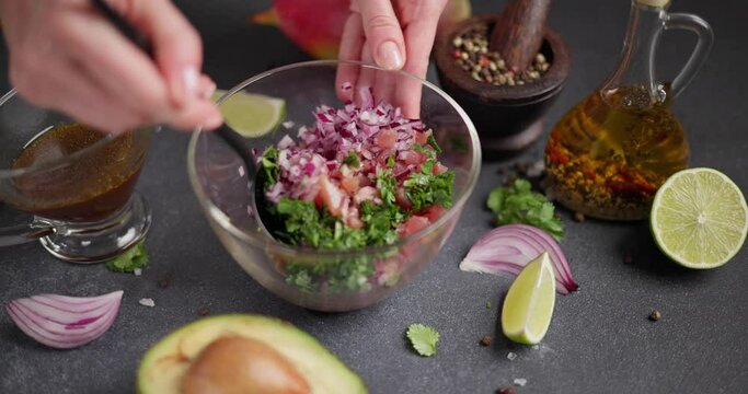 Woman mixing chopped tuna, cilantro and onion in a glass bowl cooking traditional tuna tartare