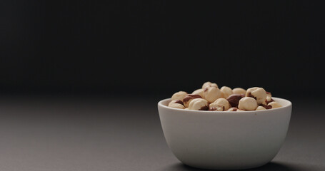 roasted hazelnuts in white bowl on black background