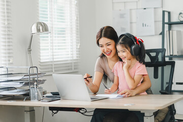 Smiling mother and daughter enjoying online communication together at home office.