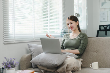 Happy asian woman waving during a video call on laptop at home. Work life balance concept