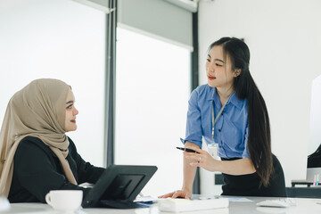 Two colleagues discuss marketing report in modern office meeting.