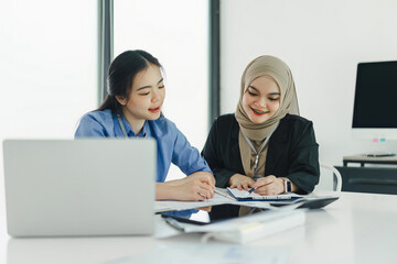 Obraz premium Diverse businesspeople smiling while working together on a laptop.