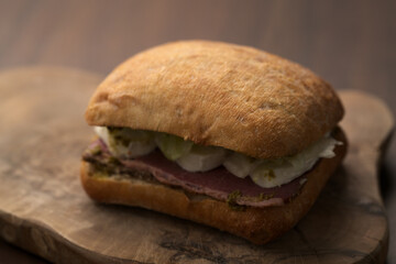 Roast beef and mozzarella sandwich with ciabatta bun on olive board