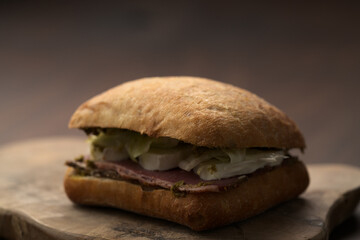 Roast beef and mozzarella sandwich with ciabatta bun on olive board