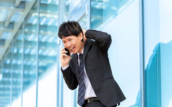 謝りながらスマホで話す男性ビジネスマン
