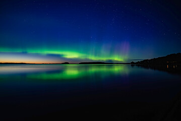 Northern light dancing over calm lake in Farnebofjarden national park in north of Sweden