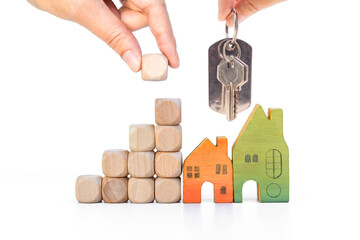 Miniature house and wooden cube stack with hand holding wooden cube isolate on white background, building block to success, buy new property goal