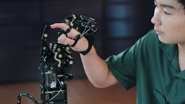 In a technical college an enthusiastic Asian teenage boy tests a robot hand and arm exploring technology for educational skill development. Embracing AI in futuristic learning.