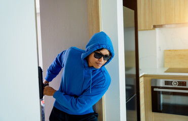 Burglar breaking in an apartment to steal something.