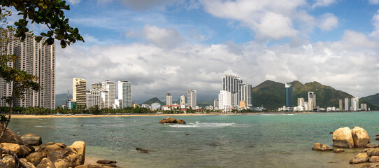 Nha Trang's scenic coastline with rocky shore, and modern high-rise hotels. coast meets sandy...