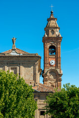 Church with belfry and clock under blue sky in Italy.