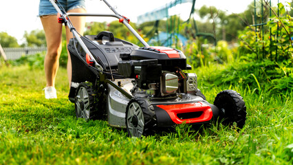 Girl with a lawn mower at her dacha
