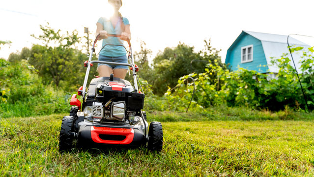 Girl with a lawn mower at her dacha