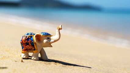 Obraz premium Elephant figurine on the beach sunbathing, vacation and travel concept