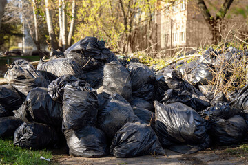 Pile of black garbage bags near a house, awaiting disposal