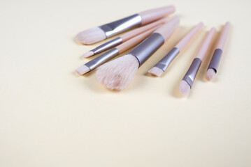 Set of brushes for cosmetics isolated on a beige background.
