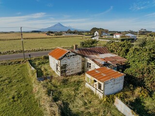 Abandoned and destroyed historic huse in overgrown grass in  Hāwera, Taranaki, New Zealand. © Zenstratus