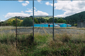 Fototapeta premium Abandoned tennis court overgrown with grass in Mapiu, Waikato, New Zealand.
