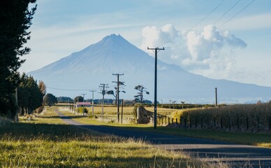 Country road, farmland and the volcano of Mt Taranaki, Taranaki, New Zealand.