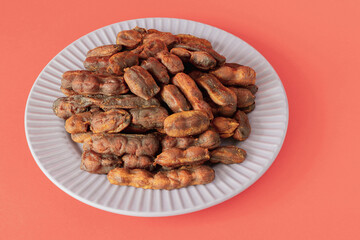 Sweet, spicy tamarind tree fruit in a round plate on a pink background
