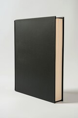 Standing black hardcover book on clean white surface. Minimalistic design mockup.