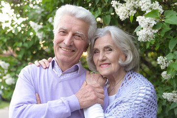 Portrait of beautiful senior couple by lilacs in the park