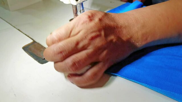 male tailor who is sewing cloth using a sewing machine to make clothes