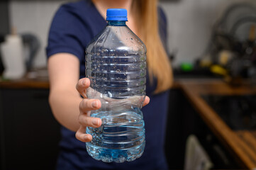 Kobieta trzyma w dłoni butelkę plastikowa z wodą mineralną niegazowaną